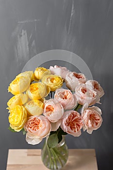 Bouquet of soft pink and yellow garden roses in a glass vase. Floral still life.