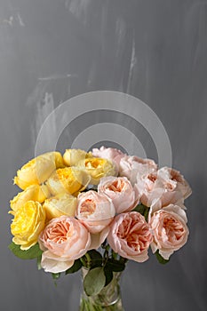 Bouquet of soft pink and yellow garden roses in a glass vase. Floral still life.