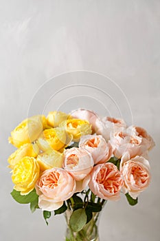 Bouquet of soft pink and yellow garden roses in a glass vase. Floral still life.