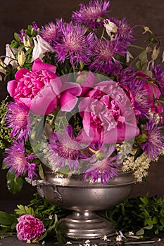 Bouquet of spring flowers in a pewter vase on a dark background