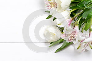 bouquet of spring flowers on a white wooden background with place for text.