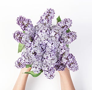 Bouquet of spring lilac flowers in woman`s hand isolated on white background. Flat lay
