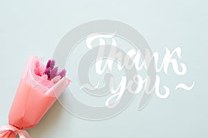Bouquet of stabilized flowers and thank you lettering on blue background photo