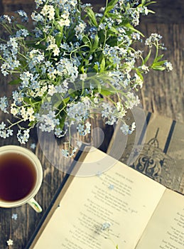 Bouquet of summer blue flowers, cup of tea and vintage books