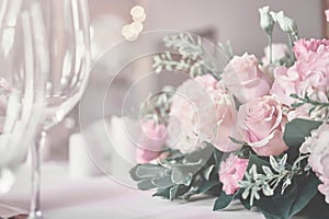 Bouquet on the table. Wine glasses in the foreground