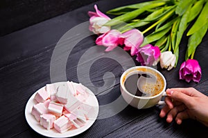 Bouquet of tender pink tulips and hands holding cup of coffee an