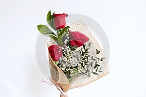 Bouquet of three red roses with decorative greens and paniculata