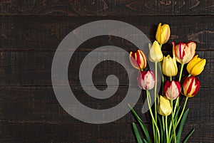 Bouquet of tulips on black rustic wooden background with copy space for message. Spring flowers. Greeting card or mock up for