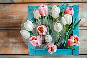 bouquet of tulips in box on a wooden background with a place for the inscription, top view