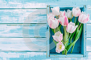 bouquet of tulips in box on a wooden background with a place for the inscription, top view