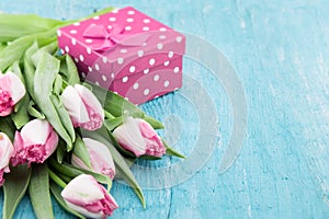 Bouquet of Tulips and gift box on turquoise rustic wooden background with copy space for message. Spring flowers. Greeting card f