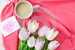 Bouquet of tulips with a mug of coffee and a gift in a red box on a pink cloth. International Women`s Day, Valentine`s Day, Moth