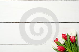 Bouquet of tulips at right corner on white wooden background . Top view, frame, border, copy space. Greeting card for womans day,