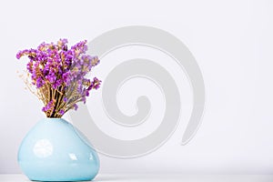 Bouquet of violet flowers in a blue vase over a white background