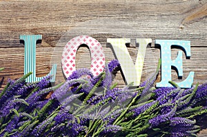 Bouquet of violet wild summer flowers and the message on love from bright letters.