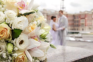 Bouquet of wedding flowers in the foreground. on the background of a wedding couple are standing in an embrace. photo near the reg