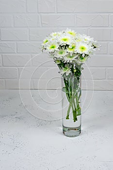 Bouquet of white chrysanthemums in a glass vase on a white background and a wooden table. Mother's day card. Beautiful