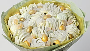 Bouquet of white marshmallows, decorated with golden sweets on a white background