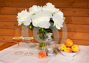 Bouquet of white peonies, glasses of wine, lantern and peaches