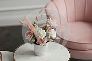 Bouquet of white and pink flowers in a white vase on a coffee table