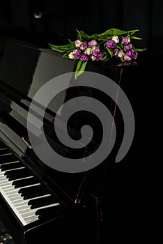 A bouquet of white and purple tulips on the lid of a closed piano