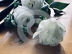 Bouquet of white roses in bag on wooden table.