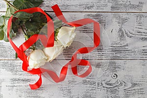 Bouquet of white roses decorated with ribbon on white wooden background