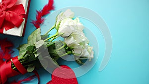 Bouquet of white roses with red bow on blue background. Boxed gift on side