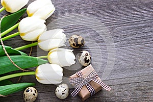 Bouquet white tulip flowers with easter eggs on old wooden tabl