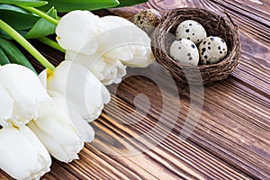 Bouquet white tulip flowers with easter eggs on old wooden tabl