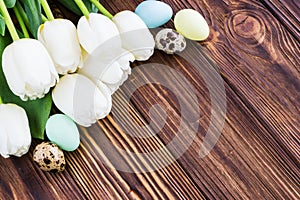 Bouquet white tulip flowers with easter eggs on old wooden tabl