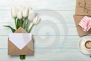 A bouquet of white tulips and envelope with a stickers with clothespins on a rope and blue wooden boards. Top view with place for