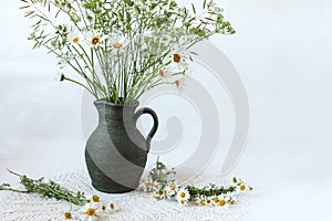Bouquet of wild flowers in a ceramic vase on a background of lace napkin