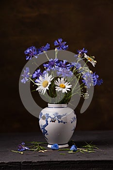 Bouquet of wild flowers in a porcelain vase on a dark background