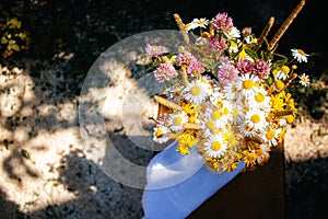 A bouquet of wild flowers in a vase stands in the garden. daisies, clover and sedge in a bouquet