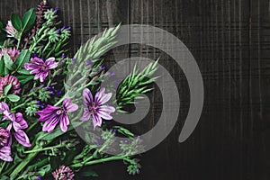 Bouquet of wild meadow flowers on dark wooden background.