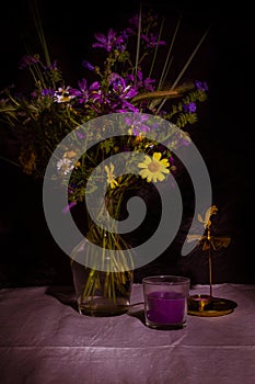 Bouquet of wild natural flowers in transparent glass vase on wooden table