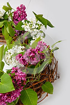 Bouquet wreath of lilac flowers on white wooden background.