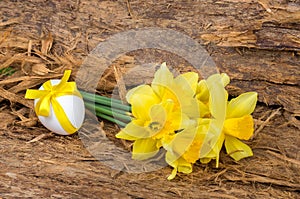 Bouquet of yellow daffodils and chicken egg with a ribbon