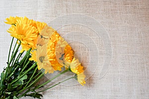 A bouquet of yellow flowers on a burlap backgound