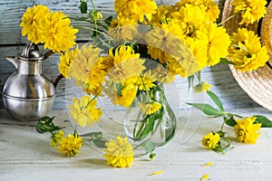 Bouquet of yellow flowers in glass vase on wooden background, still life with yellow summer flowers