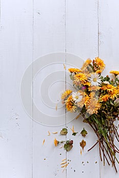 Bouquet of yellow and orange flowers on a white wooden table