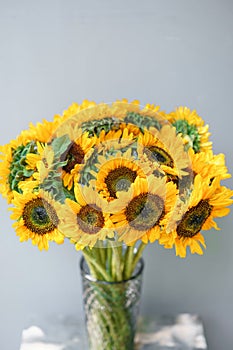 Bouquet of yellow sunflowers , flower in vase on old vintage table. Room morning. Gray background. Colors of autumn and