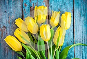 Bouquet of yellow tulips on a blue rustic background