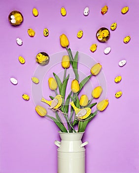 Bouquet of yellow tulips with Easter decorations on a purple background