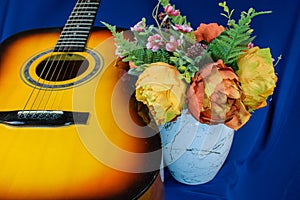 Bouquet of yellow tulips and guitar on blue background