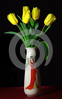 A bouquet of yellow tulips in a porcelain vase on a black background. A gift for the woman you love