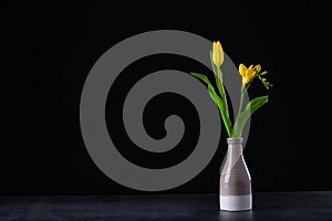 A bouquet of yellow tulips in a vase on the floor