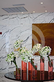 Bouquets of white lilies stand at an angle in transparent vases with red water on a round black table