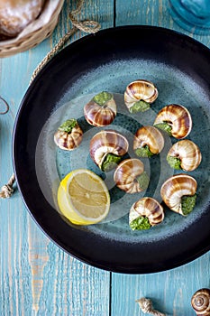 Bourguignonne snail with lemon. Blue wooden background.